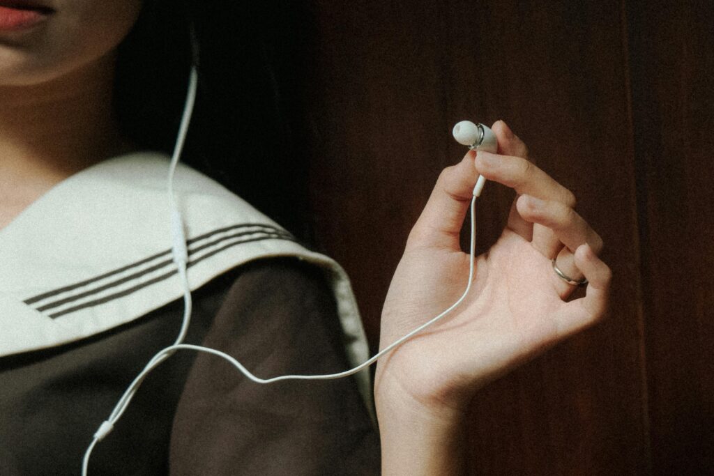 A close-up image of a hand holding earphones next to a person wearing navy attire, suggesting a relaxed mood.