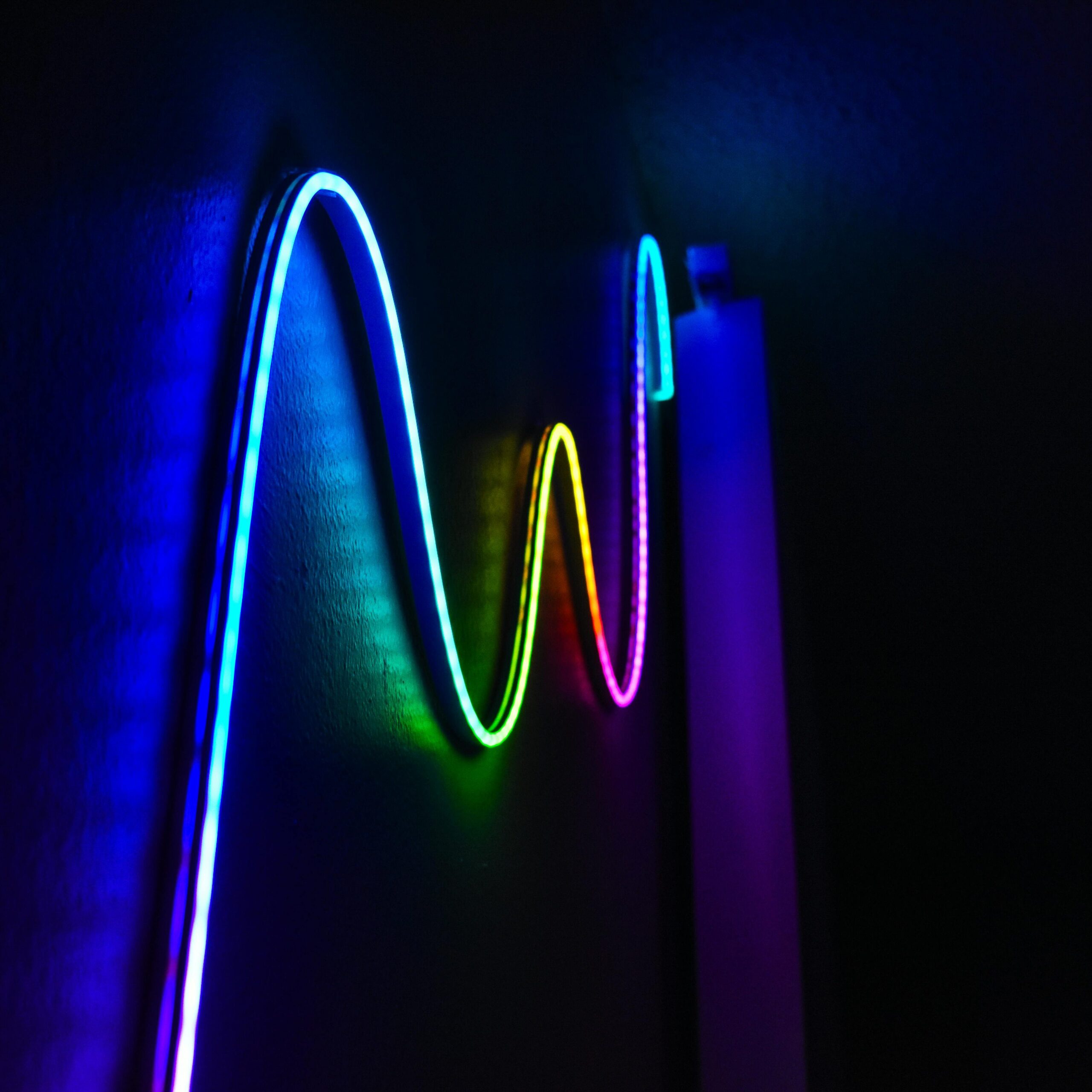 Colorful neon wave pattern LED lights illuminating a dark room for a modern home decor aesthetic.